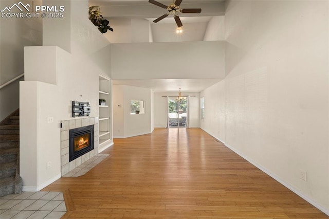 3245 Chestnut Glen Ln, Colorado Springs, CO 80918 - unfurnished living room featuring light wood finished floors, ceiling fan, a tile fireplace, stairway, and built in shelves