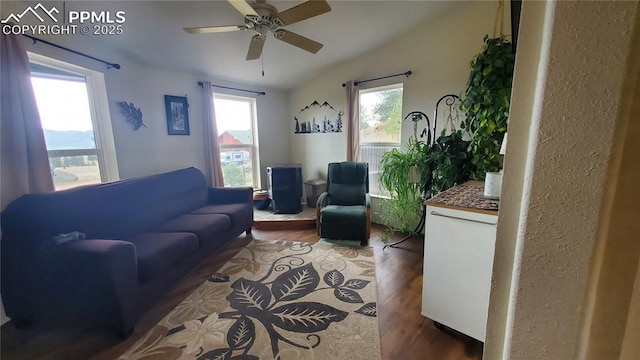 living area with a ceiling fan, vaulted ceiling, and wood finished floors