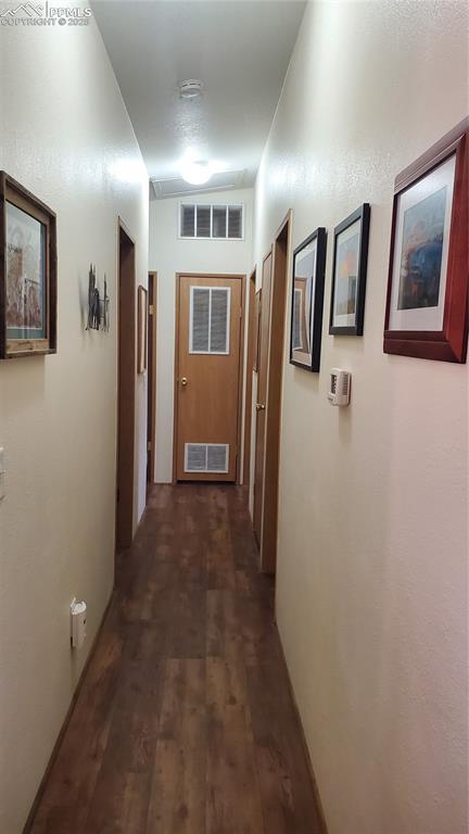 hallway featuring dark wood-style flooring and visible vents