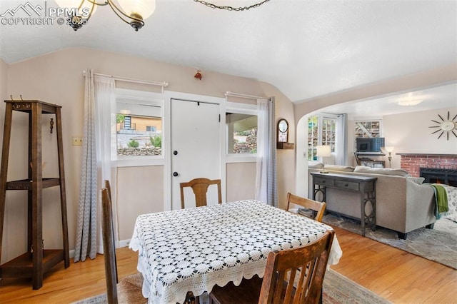 25 Highland St, Colorado Springs, CO 80906 - dining room featuring vaulted ceiling, light wood-style floors, arched walkways, and a fireplace