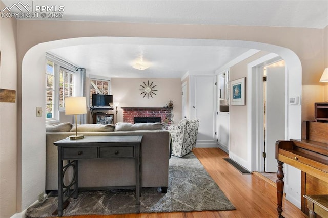 25 Highland St, Colorado Springs, CO 80906 - living room with arched walkways, wood finished floors, a fireplace, and baseboards