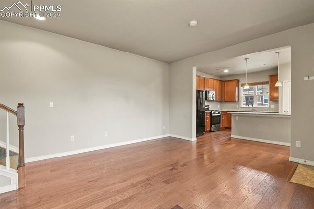 8806 Bella Flora Hts, Colorado Springs, CO 80924 - unfurnished living room with light wood finished floors, a sink, baseboards, and stairs