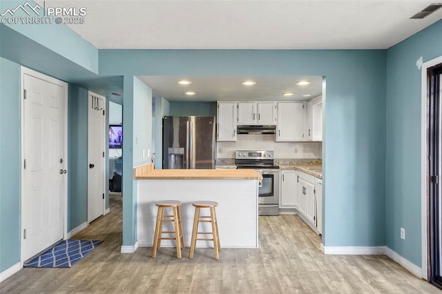 4720 Live Oak Dr, Colorado Springs, CO 80916 - kitchen with stainless steel appliances, under cabinet range hood, light wood finished floors, a peninsula, and white cabinetry