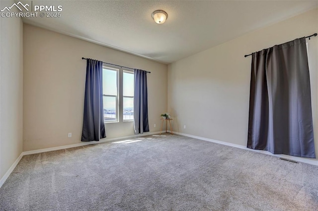 spare room featuring carpet floors, baseboards, and visible vents