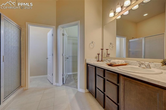 bathroom with double vanity, a spacious closet, a sink, and a stall shower