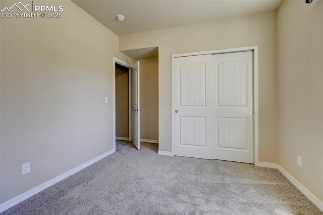 unfurnished bedroom featuring carpet floors, baseboards, and a closet