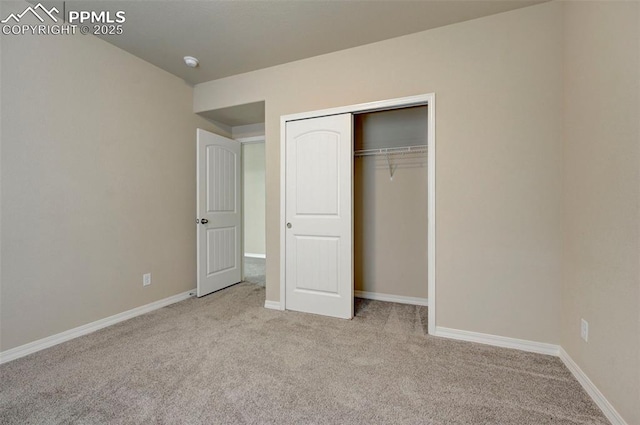 unfurnished bedroom featuring carpet floors, baseboards, and a closet