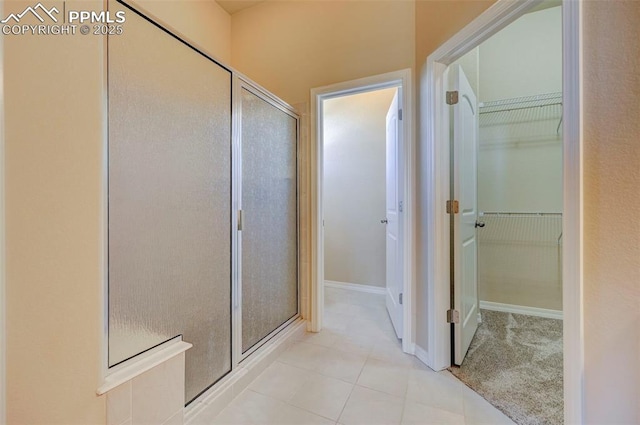 bathroom with a walk in closet, a stall shower, and tile patterned floors
