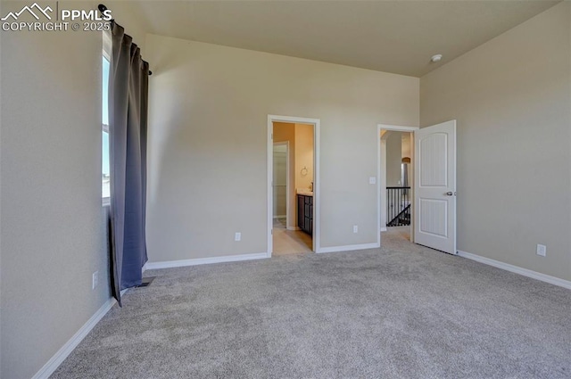 unfurnished bedroom featuring connected bathroom, baseboards, and light carpet