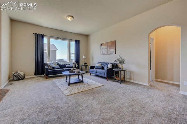 living room with baseboards, arched walkways, and carpet