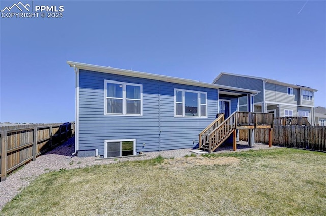 back of property featuring a lawn, a fenced backyard, a wooden deck, and stairway