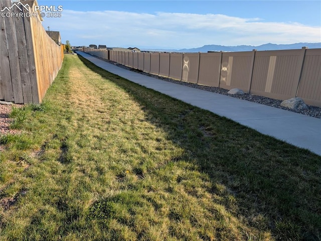 view of yard featuring a mountain view and a fenced backyard