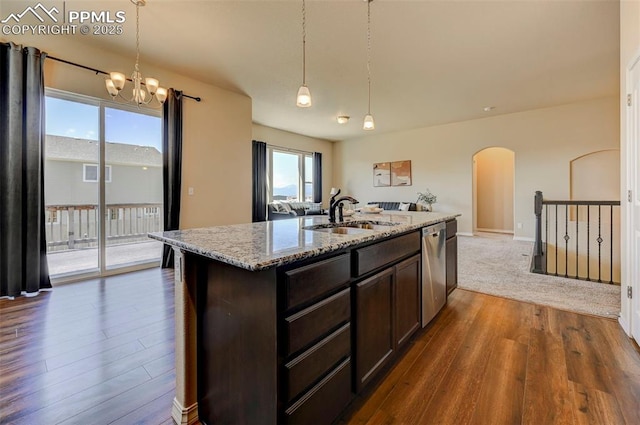 kitchen featuring dark brown cabinetry, arched walkways, stainless steel dishwasher, a sink, and dark wood-style floors