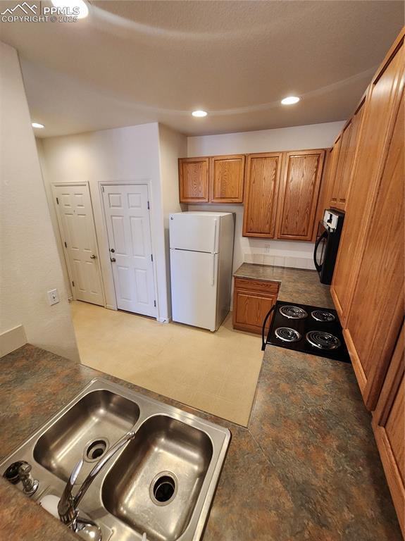 3928 Diamond Ridge Vw, Colorado Springs, CO 80918 - kitchen featuring freestanding refrigerator, a sink, stove, brown cabinets, and recessed lighting