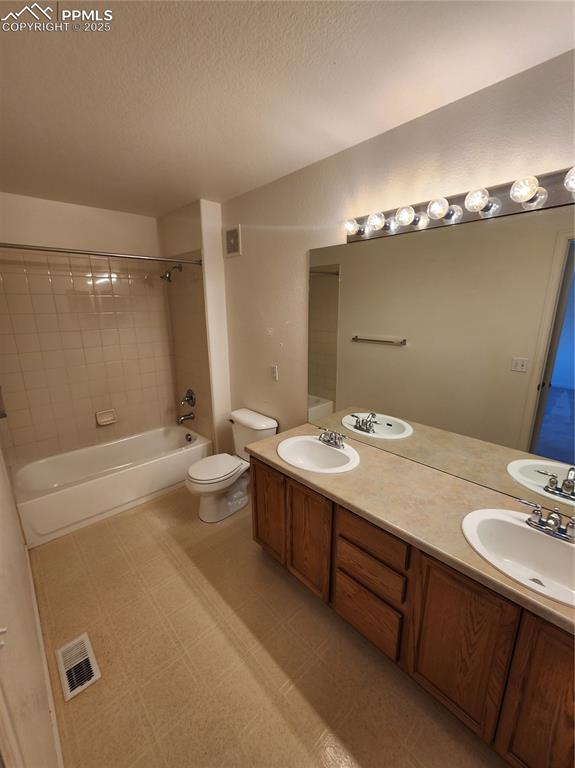 3928 Diamond Ridge Vw, Colorado Springs, CO 80918 - bathroom featuring toilet, tub / shower combination, double vanity, and a textured ceiling