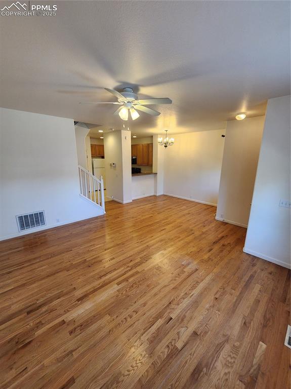 3928 Diamond Ridge Vw, Colorado Springs, CO 80918 - unfurnished living room with a ceiling fan, light wood-style flooring, a chandelier, and stairs