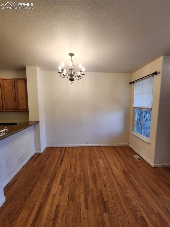 3928 Diamond Ridge Vw, Colorado Springs, CO 80918 - unfurnished dining area featuring a chandelier, wood finished floors, a textured ceiling, and baseboards
