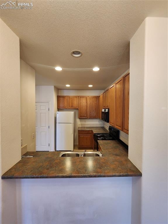 3928 Diamond Ridge Vw, Colorado Springs, CO 80918 - kitchen with freestanding refrigerator, black range with gas stovetop, a peninsula, recessed lighting, and brown cabinetry