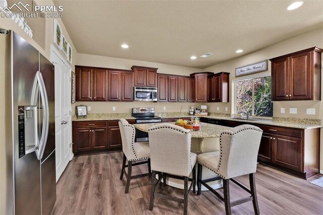 8356 Longleaf Ln, Colorado Springs, CO 80927 - kitchen featuring a kitchen breakfast bar, light wood-style flooring, appliances with stainless steel finishes, and a center island