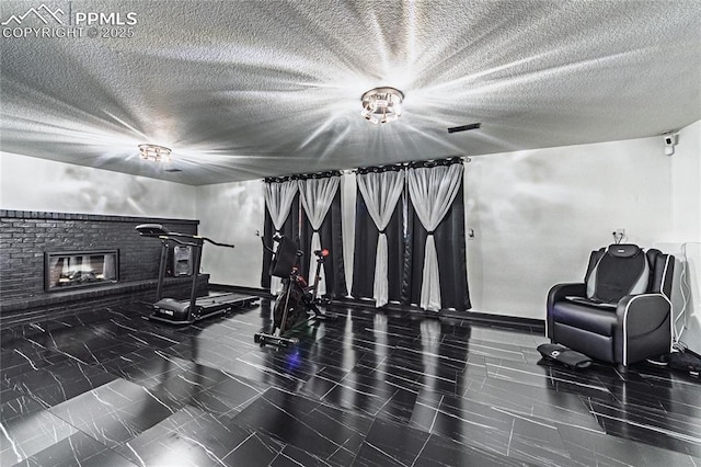 workout area featuring baseboards, a textured ceiling, and a fireplace