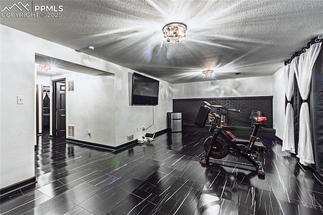 interior space featuring baseboards, a textured ceiling, and visible vents