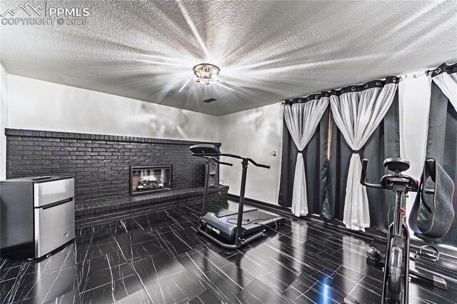 workout room with a textured ceiling and a fireplace