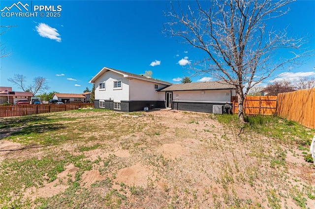 rear view of house with a fenced backyard and stucco siding
