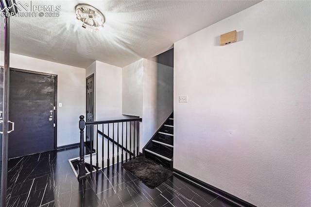 stairway featuring a textured ceiling and baseboards