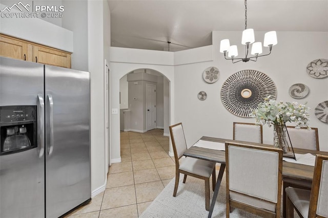 dining room featuring light tile patterned floors, arched walkways, baseboards, and a notable chandelier