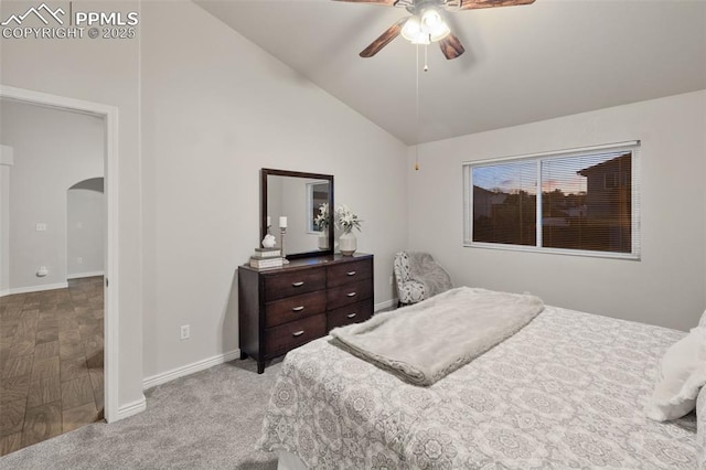carpeted bedroom featuring baseboards, arched walkways, a ceiling fan, and vaulted ceiling
