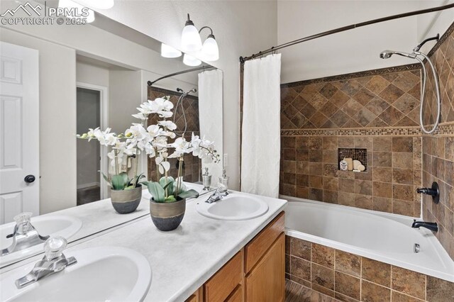 full bath with double vanity, tiled shower / bath, and a sink
