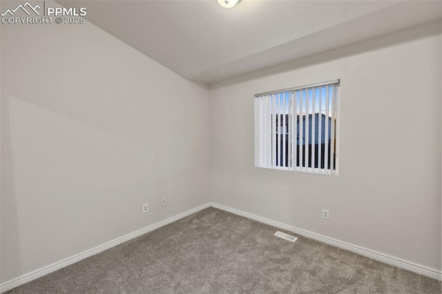 carpeted spare room with visible vents, baseboards, and vaulted ceiling