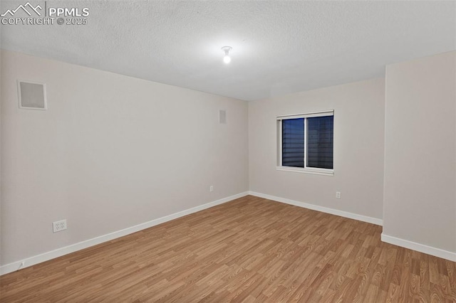 unfurnished room with baseboards, a textured ceiling, and light wood-style flooring