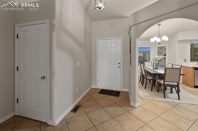 entrance foyer with arched walkways, a chandelier, baseboards, light tile patterned floors, and visible vents