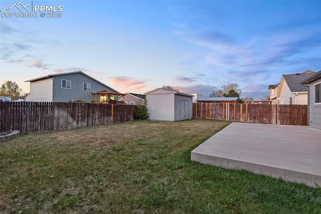 view of yard featuring a fenced backyard, a storage unit, a patio, and an outbuilding