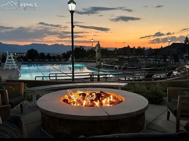 5019 Petrified Forest Trl, Colorado Springs, CO 80924 - pool at dusk with a fire pit, a community pool, a mountain view, and a patio