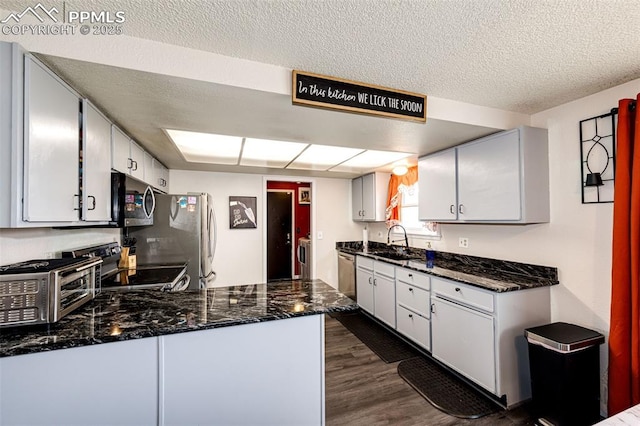 1085 6th St, Limon, CO 80828 - kitchen with a sink, a textured ceiling, dark stone countertops, stainless steel appliances, and dark wood-type flooring