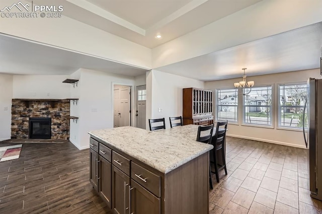4157 Gray Fox Hts, Colorado Springs, CO 80922 - kitchen with a fireplace, baseboards, a breakfast bar area, dark wood-type flooring, and a chandelier