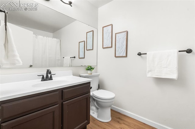 bathroom with wood finished floors, baseboards, toilet, and vanity