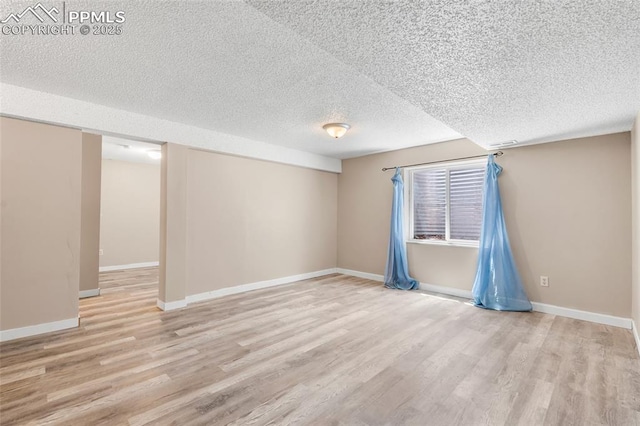 unfurnished room featuring a textured ceiling, wood finished floors, and baseboards