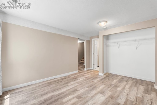 unfurnished bedroom featuring light wood-style flooring, a closet, and baseboards