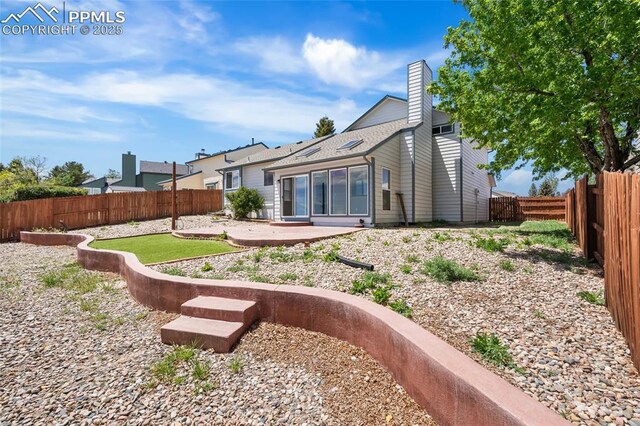 rear view of property with a chimney, a patio, and a fenced backyard