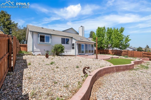 back of property featuring a patio, a chimney, a fenced backyard, and a shingled roof