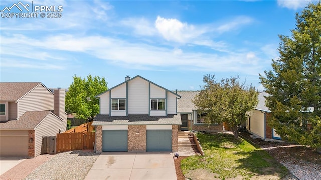 tri-level home with brick siding, concrete driveway, fence, and an attached garage