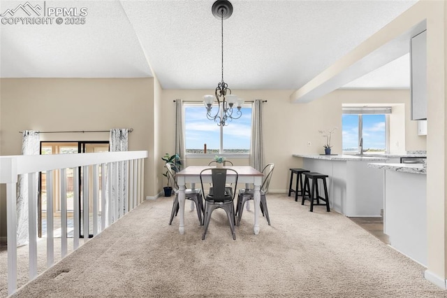 carpeted dining room featuring a chandelier, a textured ceiling, a sink, and baseboards