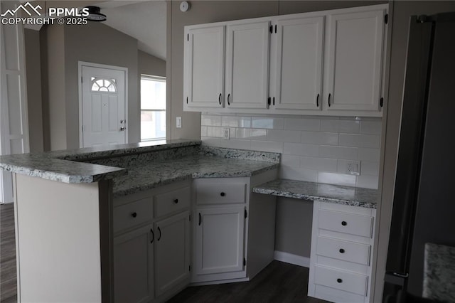 4663 Pine Marten Pt, Colorado Springs, CO 80922 - kitchen featuring white cabinets, a peninsula, dark wood-style floors, and decorative backsplash