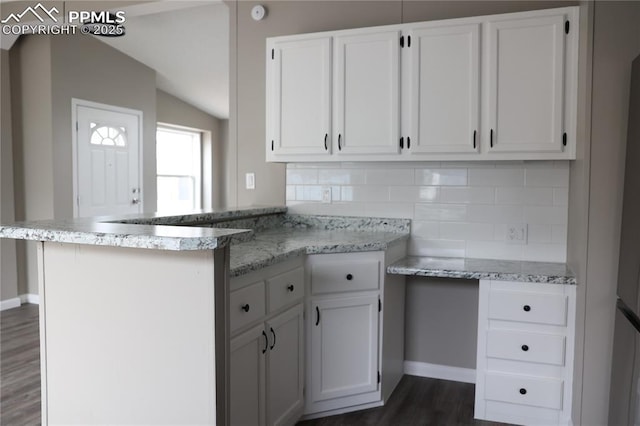 4663 Pine Marten Pt, Colorado Springs, CO 80922 - kitchen with a peninsula, lofted ceiling, dark wood-style floors, white cabinets, and tasteful backsplash