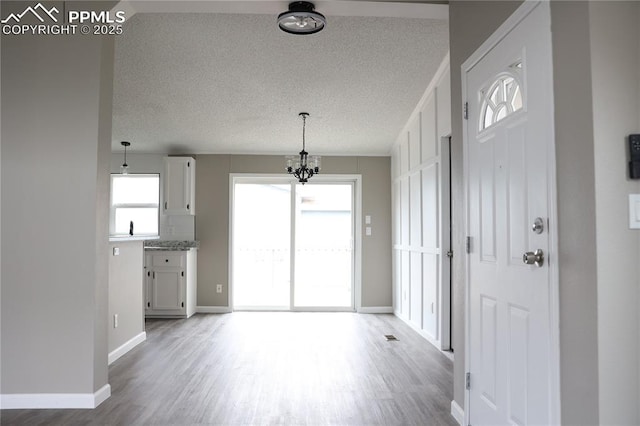 4663 Pine Marten Pt, Colorado Springs, CO 80922 - foyer entrance with a textured ceiling, baseboards, a notable chandelier, and wood finished floors