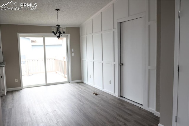 4663 Pine Marten Pt, Colorado Springs, CO 80922 - unfurnished dining area featuring an inviting chandelier, a textured ceiling, baseboards, wood finished floors, and visible vents