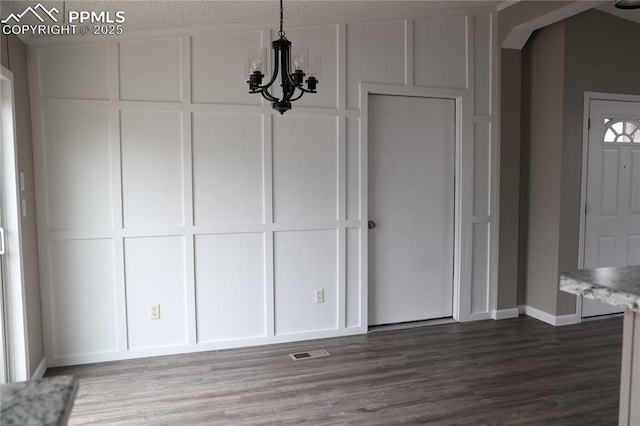 4663 Pine Marten Pt, Colorado Springs, CO 80922 - unfurnished dining area with an inviting chandelier, a decorative wall, baseboards, wood finished floors, and visible vents